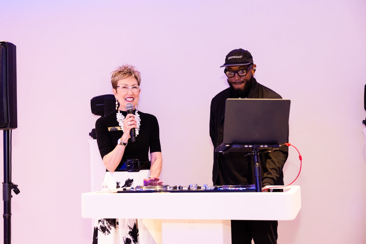 Bernhardt Director of Brand Development Heather Eidenmiller commandeers DJ RaQuest's booth to announce the band is about to start.